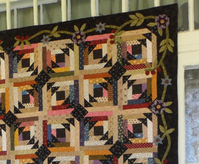 scrappy lap quilt pattern with floral applique accent