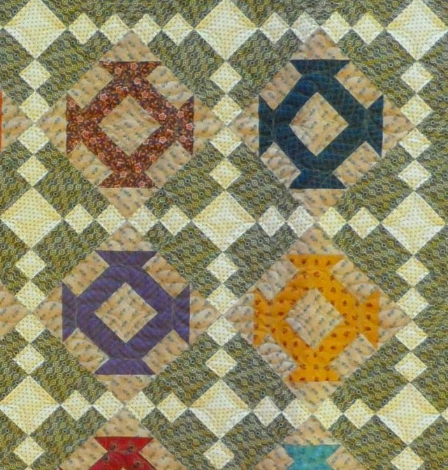 scrappy churn dash blocks make up this scrappy lap quilt